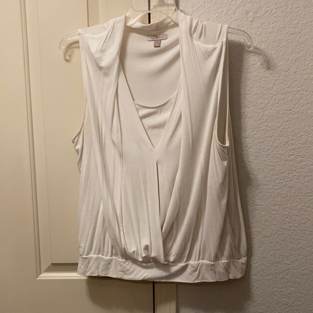 Sleeveless white shirt with inset and overlap.